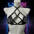 Black strappy top with decorative elements on a mannequin against a white background