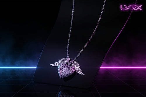 Silver necklace with heart and wing pendant on a pink fabric background