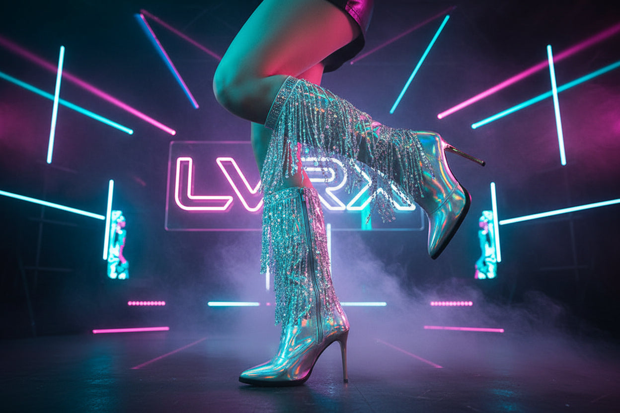 Shiny high-heeled boots with fringe details worn by a person 