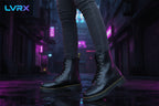 Black leather boots worn with gray jeans on a concrete step.